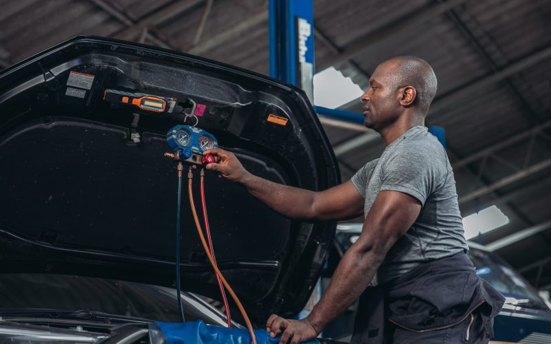 A skilled automotive technician uses manifold gauges to diagnose and service the air conditioning system of a vehicle in the garage workshop, ensuring optimal performance and efficiency.