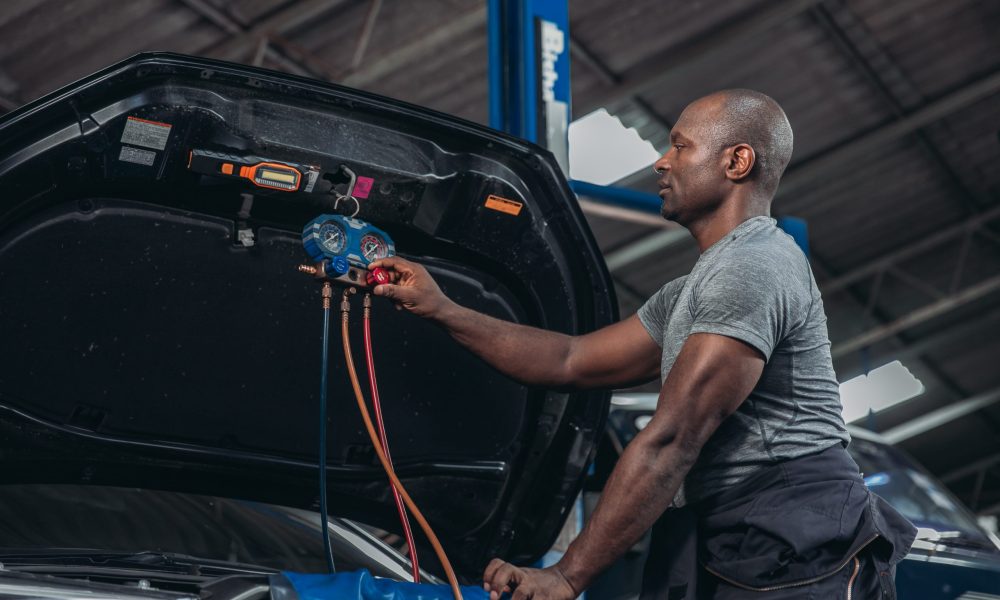A skilled automotive technician uses manifold gauges to diagnose and service the air conditioning system of a vehicle in the garage workshop, ensuring optimal performance and efficiency.